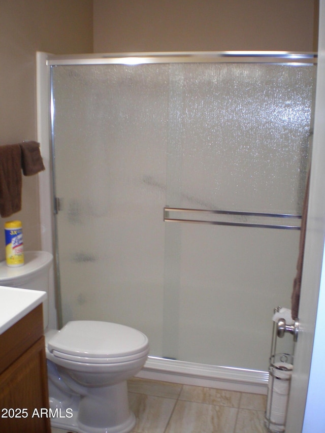 bathroom featuring toilet, a stall shower, vanity, and tile patterned floors