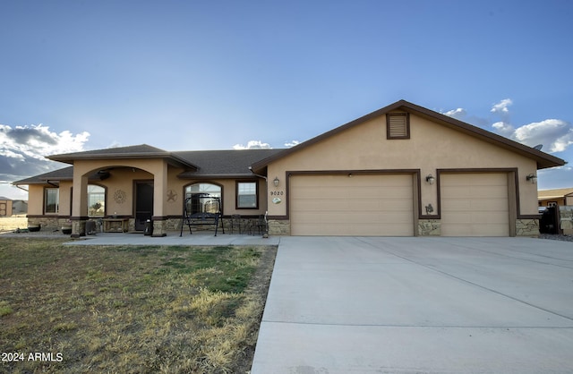 view of front facade with stucco siding, stone siding, and a garage