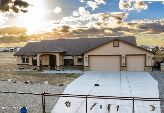 view of front of house with fence, an attached garage, stucco siding, concrete driveway, and stone siding