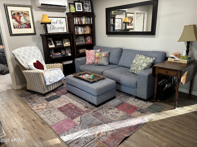 living room featuring baseboards, an AC wall unit, and wood finished floors