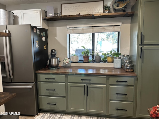 kitchen featuring open shelves, stainless steel fridge, wood counters, and green cabinets