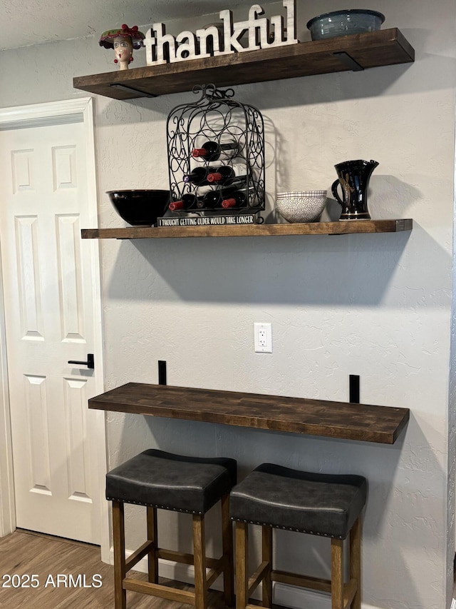 bar featuring a textured wall and wood finished floors