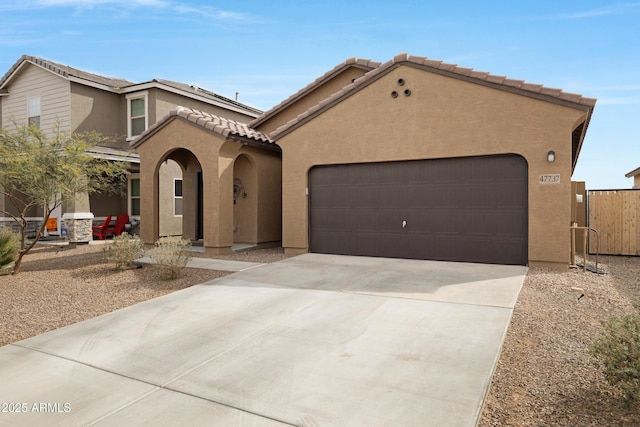 mediterranean / spanish-style house featuring a garage, a tile roof, driveway, and stucco siding