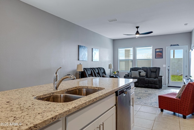 kitchen with white cabinets, dishwasher, light stone counters, a sink, and light tile patterned flooring