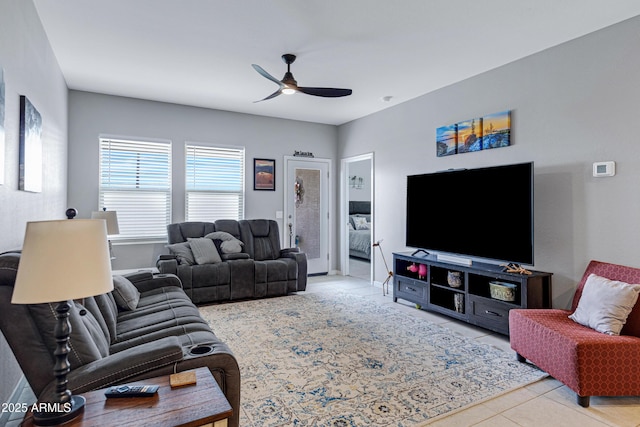tiled living area with ceiling fan and baseboards