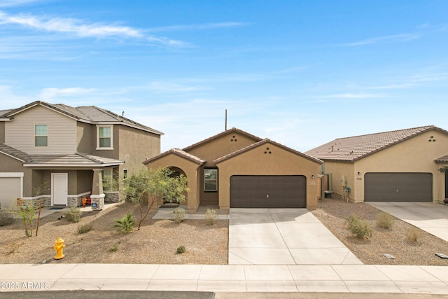 view of front facade featuring a garage, a tile roof, concrete driveway, and stucco siding