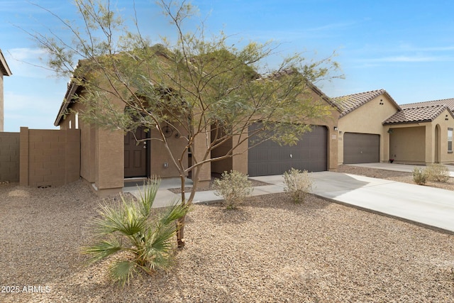 view of front of home featuring stucco siding, concrete driveway, fence, a garage, and a tiled roof