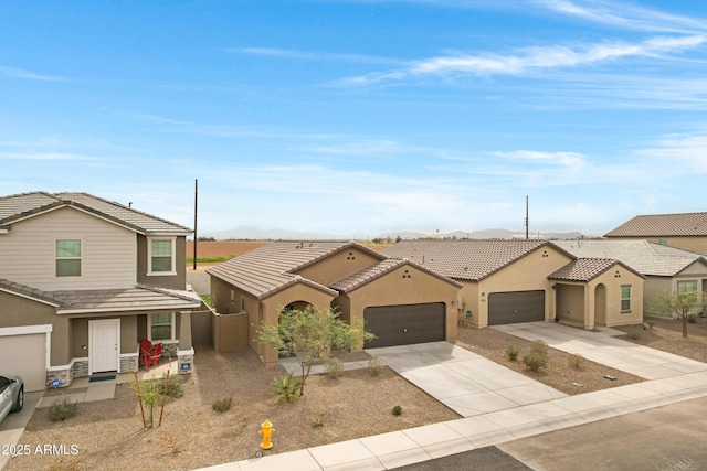 view of front facade featuring a tile roof, stucco siding, concrete driveway, an attached garage, and a residential view