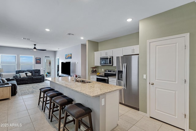 kitchen featuring a breakfast bar, light tile patterned floors, visible vents, appliances with stainless steel finishes, and a sink