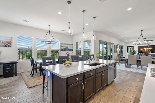 kitchen featuring dark brown cabinets, hanging light fixtures, a breakfast bar area, dishwasher, and sink