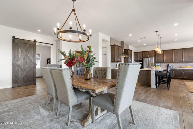 dining room featuring a barn door, a notable chandelier, and light wood-type flooring