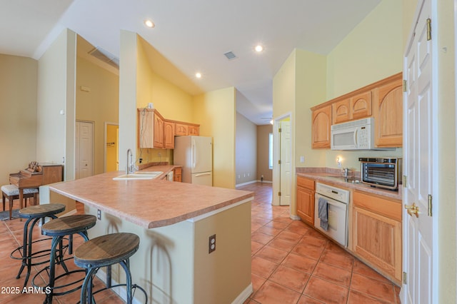 kitchen with white appliances, sink, kitchen peninsula, a breakfast bar area, and light tile patterned flooring