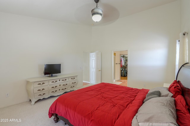 bedroom with ceiling fan, a high ceiling, and light carpet