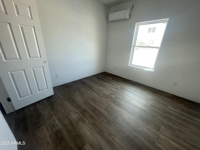 empty room featuring an AC wall unit and dark wood-style flooring