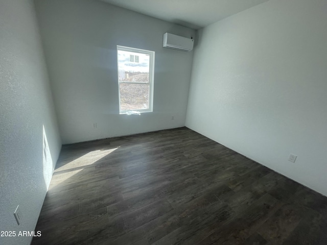 empty room with a wall mounted air conditioner and dark wood-type flooring