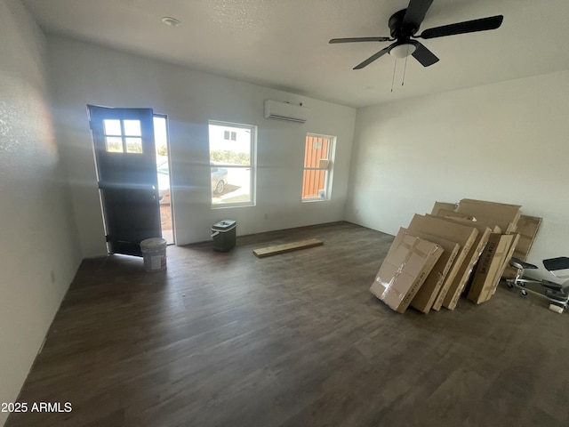 unfurnished living room with a ceiling fan, a wall unit AC, and dark wood-style flooring