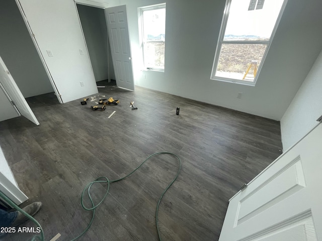 unfurnished bedroom with multiple windows and dark wood-style flooring