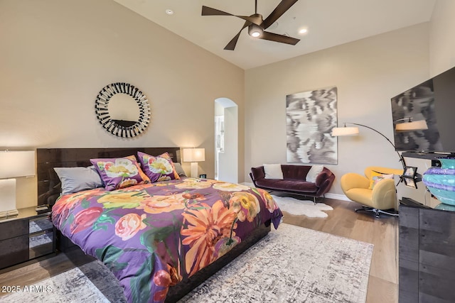 bedroom featuring arched walkways, recessed lighting, vaulted ceiling, light wood-type flooring, and baseboards