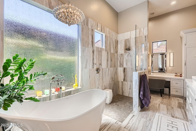 bathroom with a soaking tub, walk in shower, an inviting chandelier, and vanity