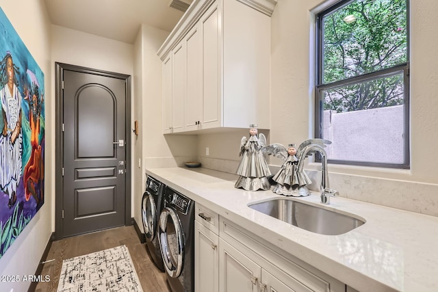 washroom with cabinet space, visible vents, washing machine and clothes dryer, light wood-style floors, and a sink