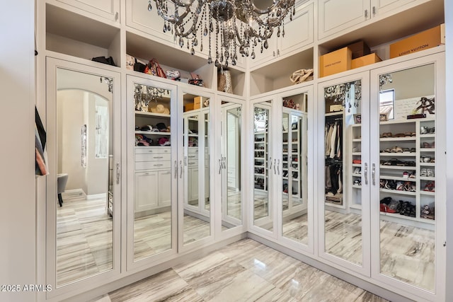 walk in closet with an inviting chandelier and arched walkways