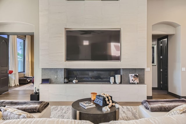 living room featuring arched walkways, wood finished floors, and baseboards