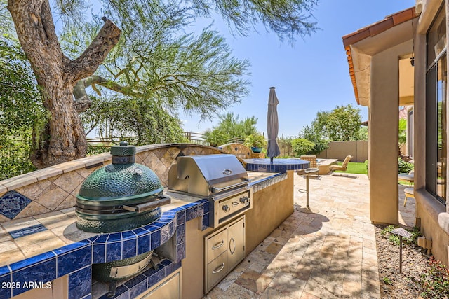 view of patio featuring a fenced backyard, a grill, and an outdoor kitchen