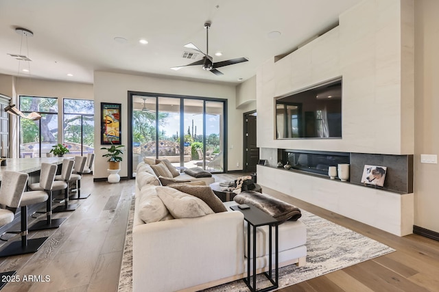 living room featuring light wood-style floors, a wealth of natural light, and visible vents