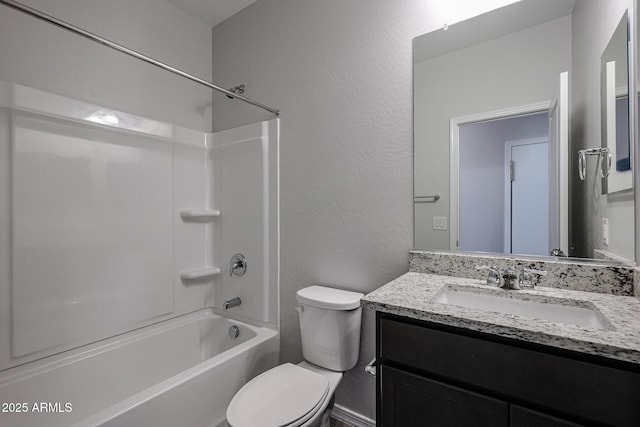 bathroom with a textured wall, vanity, toilet, and shower / washtub combination