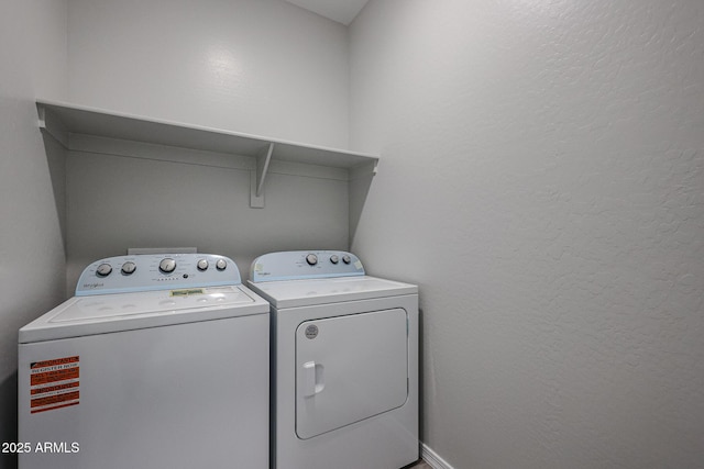 laundry area featuring washer and dryer, laundry area, and a textured wall