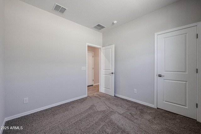 unfurnished bedroom with carpet flooring, baseboards, and visible vents