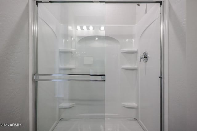 bathroom with a textured wall and a stall shower