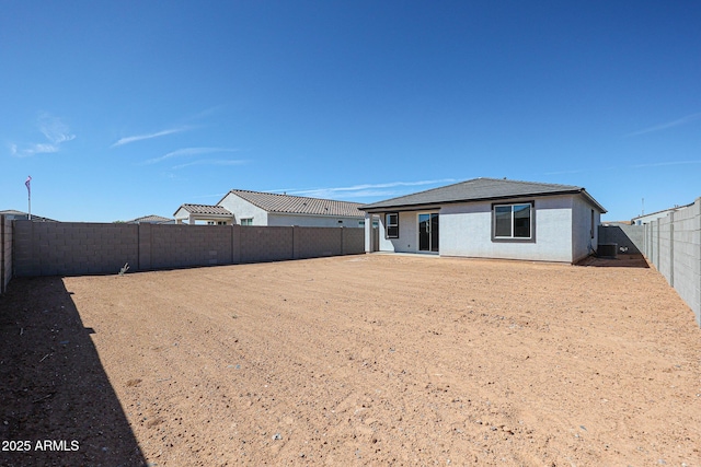 rear view of house featuring a fenced backyard and stucco siding