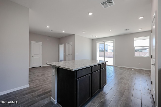 kitchen with dark cabinets, baseboards, wood finish floors, recessed lighting, and visible vents