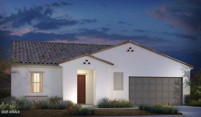 mediterranean / spanish house with a garage, concrete driveway, a tiled roof, and stucco siding