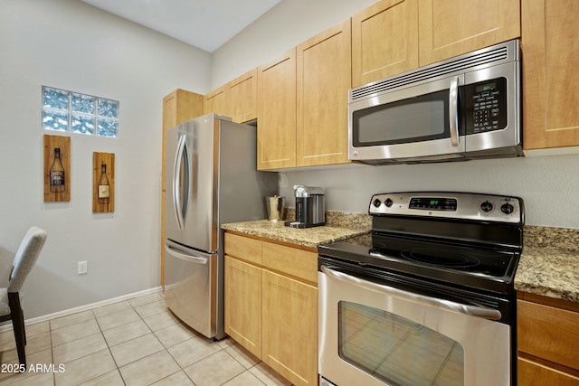 kitchen featuring light brown cabinetry, light tile patterned floors, appliances with stainless steel finishes, and light stone counters