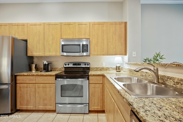 kitchen featuring light brown cabinets, a sink, light stone counters, appliances with stainless steel finishes, and light tile patterned floors