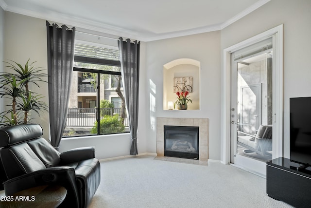 sitting room with baseboards, ornamental molding, carpet flooring, and a tiled fireplace