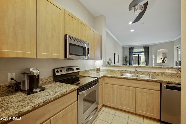 kitchen featuring light brown cabinets, crown molding, light tile patterned flooring, stainless steel appliances, and a sink