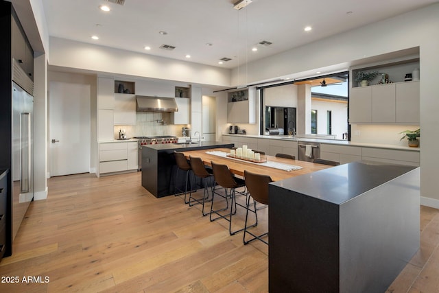 9148 N 66th Pl, Paradise Valley, AZ 85253 - kitchen featuring exhaust hood, modern cabinets, a spacious island, a breakfast bar area, and open shelves