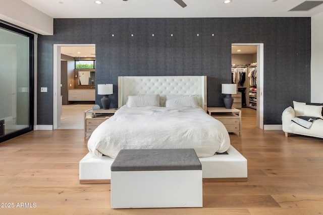 9148 N 66th Pl, Paradise Valley, AZ 85253 - bedroom with wallpapered walls, a walk in closet, light wood-style flooring, an accent wall, and baseboards