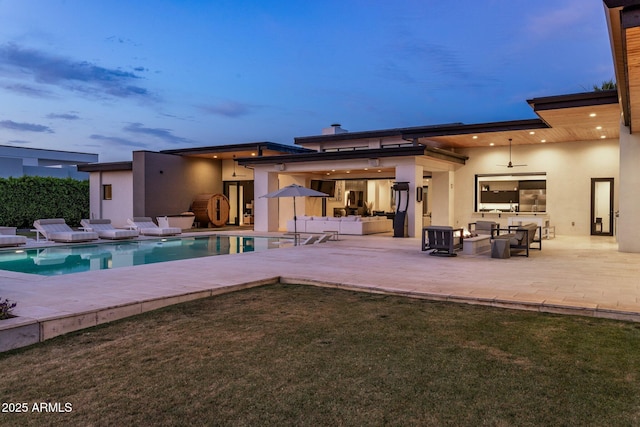 9148 N 66th Pl, Paradise Valley, AZ 85253 - back of house at dusk featuring stucco siding, an outdoor living space, a ceiling fan, a patio area, and a lawn