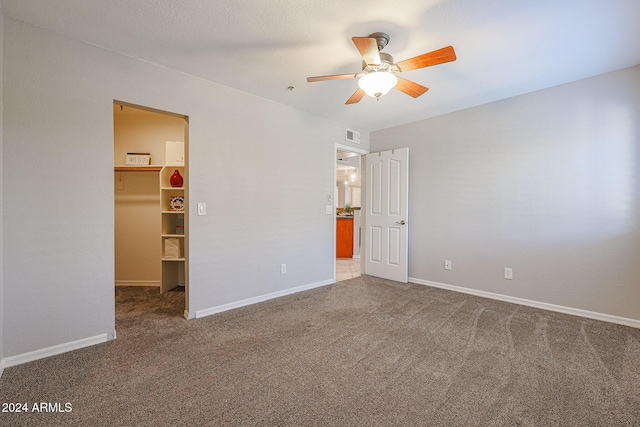 unfurnished bedroom with carpet flooring, ceiling fan, a walk in closet, and a closet