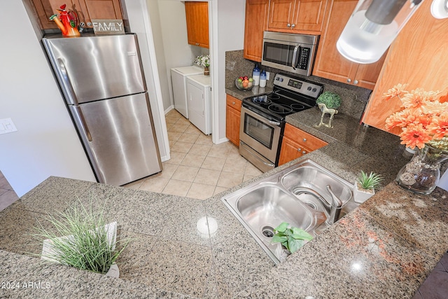 kitchen featuring sink, separate washer and dryer, kitchen peninsula, light tile patterned flooring, and appliances with stainless steel finishes