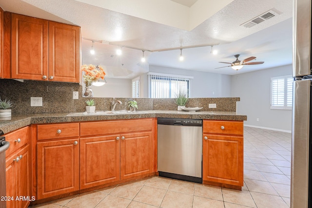 kitchen featuring rail lighting, ceiling fan, light tile patterned floors, a textured ceiling, and stainless steel appliances