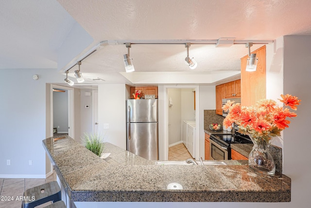 kitchen featuring kitchen peninsula, a textured ceiling, stainless steel appliances, and track lighting