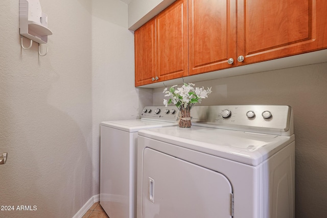 laundry room with cabinets, light tile patterned floors, and separate washer and dryer