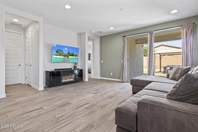 6919 S 13th Pl, Phoenix, AZ 85042 - living room featuring wood finished floors, recessed lighting, and a glass covered fireplace