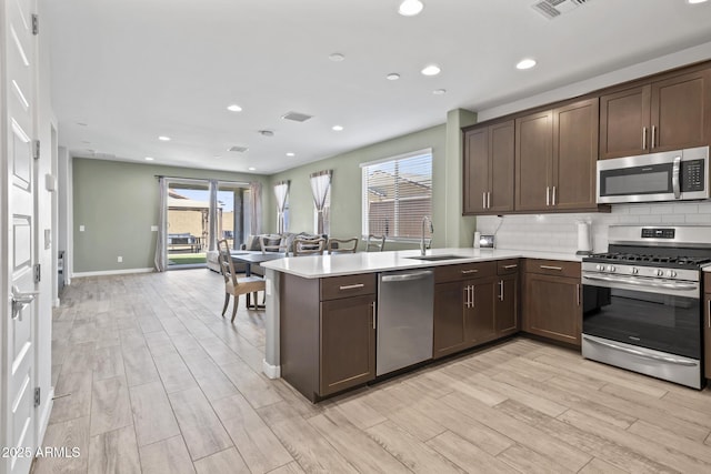 6919 S 13th Pl, Phoenix, AZ 85042 - kitchen featuring stainless steel appliances, a peninsula, light countertops, dark brown cabinets, and light wood finished floors