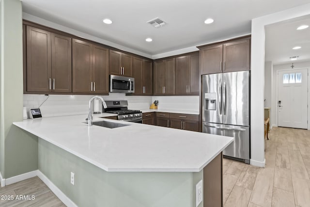 6919 S 13th Pl, Phoenix, AZ 85042 - kitchen featuring stainless steel appliances, light countertops, dark brown cabinets, a peninsula, and recessed lighting